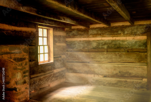 Rustic log cabin interior with light rays throughout the windows and wood floors 
