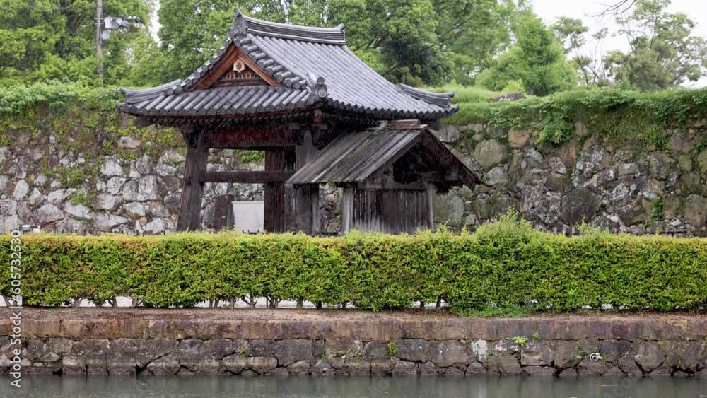 Rain falls on traditional Japanese wooden pavilion by stone castle walls Rain falls on traditional Japanese wooden pavilion by stone castle walls
