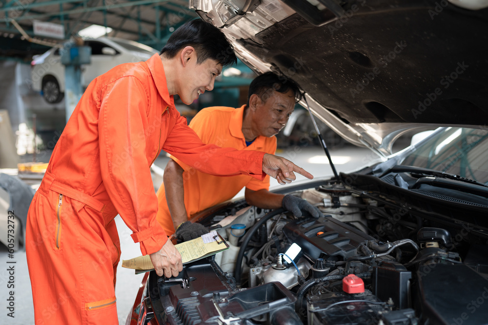 Asia mechanic man examining and maintenance to engine a vehicle car hood Asia mechanic man examining and maintenance to engine a vehicle car hood
