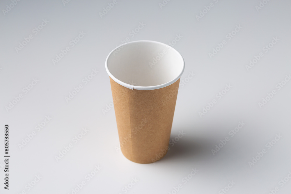 Disposable cardboard biodegradable glass on a white table, gray background. Disposable cardboard biodegradable glass on a white table, gray background.