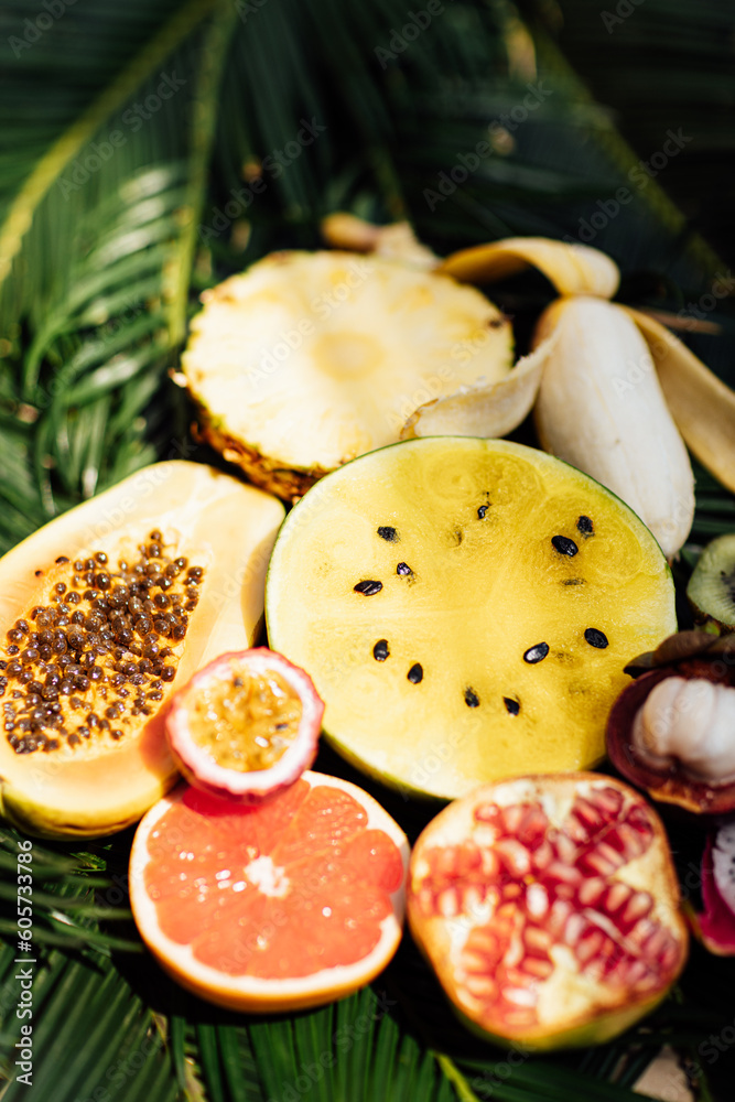 Fresh exotic fruits on green tropical palm leaves background - papaya, mango, pineapple, passion fruit, dragon fruit, watermelon. flat lay, overhead. Healthy food and diet concept. Top view.