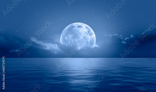 Night sky with blue moon in the clouds over the calm blue sea, many sytars in the background "Elements of this image furnished by NASA