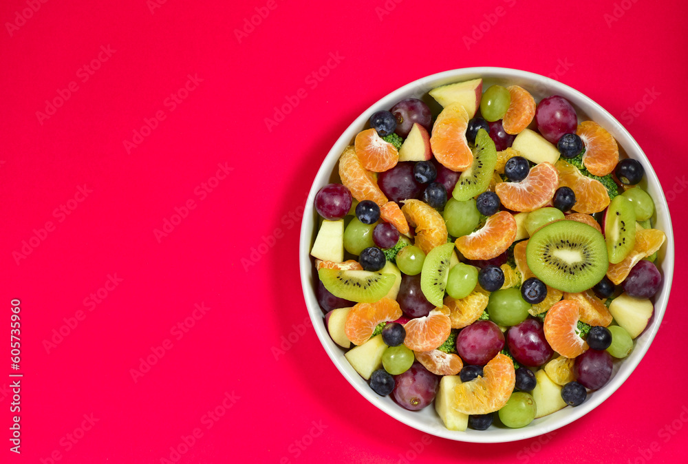 Healthy fresh fruit salad bowl on red background. Top view. Healthy food concept, healthy high vitamin fruit, mixed fruit background. Healthy fresh fruit salad bowl on red background. Top view. Healthy food concept, healthy high vitamin fruit, mixed fruit background.