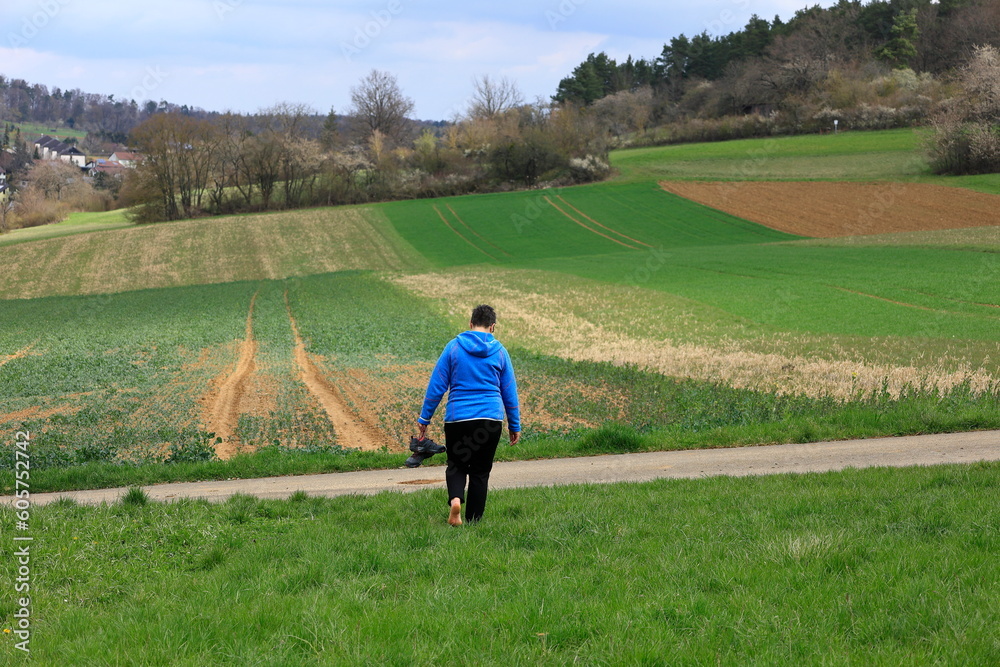 Frau geht ohne Schuhe über einen Feldweg spazieren Frau geht ohne Schuhe über einen Feldweg spazieren