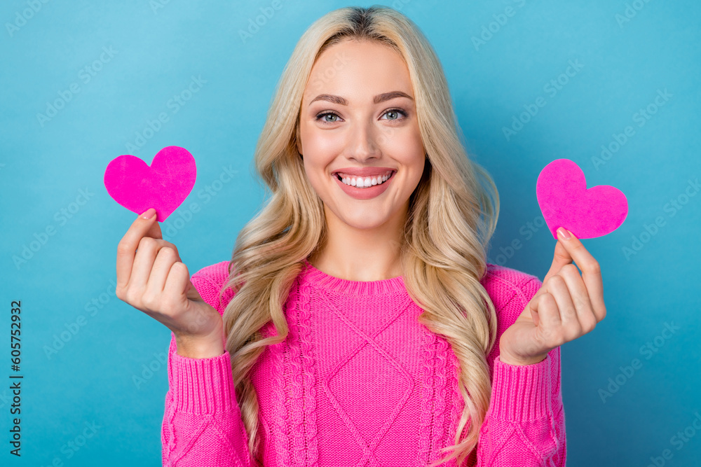 Photo of cheerful pretty lady wear pink sweater smiling rising two little hearts isolated blue color background Photo of cheerful pretty lady wear pink sweater smiling rising two little hearts isolated blue color background