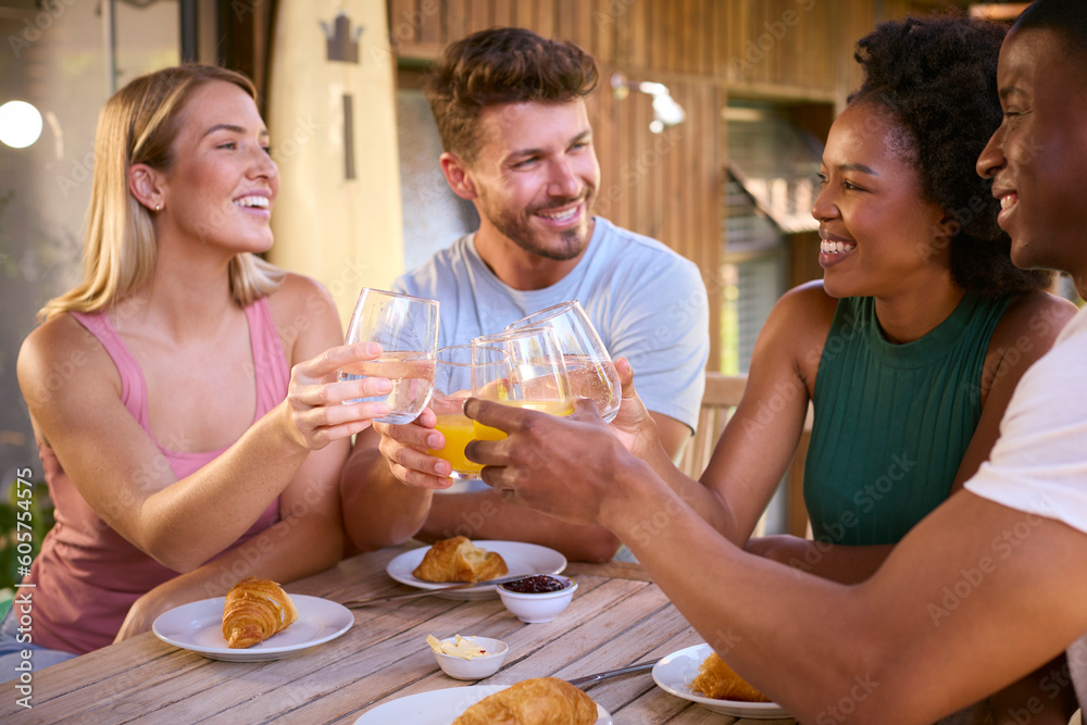Group Of Smiling Multi-Cultural Friends Eating Breakfast Outdoors At Home Making A Toast Together Group Of Smiling Multi-Cultural Friends Eating Breakfast Outdoors At Home Making A Toast Together