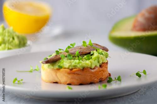 Sandwiches with sprats on toasted slices of bread. Sandwich with smoked sprat - fish, avocado and microgreens.
