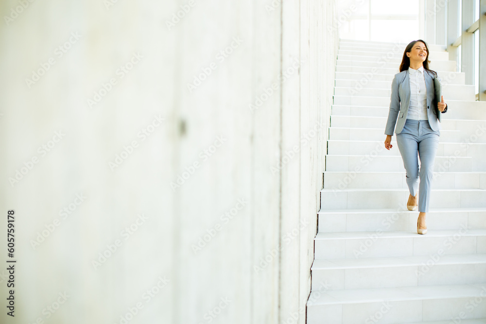 Young business woman walking down the stairs and holding laptop Young business woman walking down the stairs and holding laptop