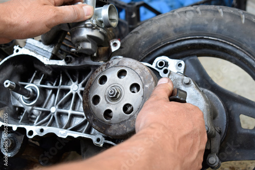 Scooter engine repair. Man's hands on the background of the engine.