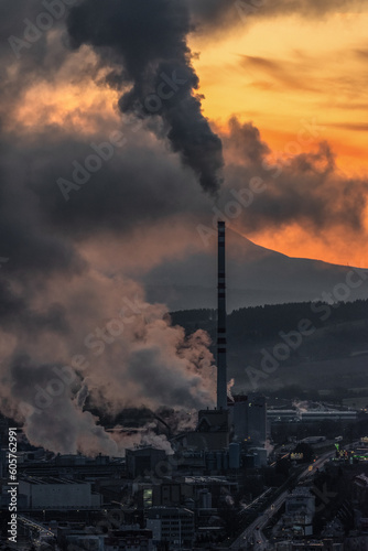 Factory with chimney and smoke and steam with colorful sunset at background