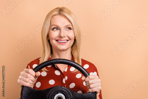 Photo of minded cheerful person toothy smile arms hold wheel look empty space isolated on beige color background