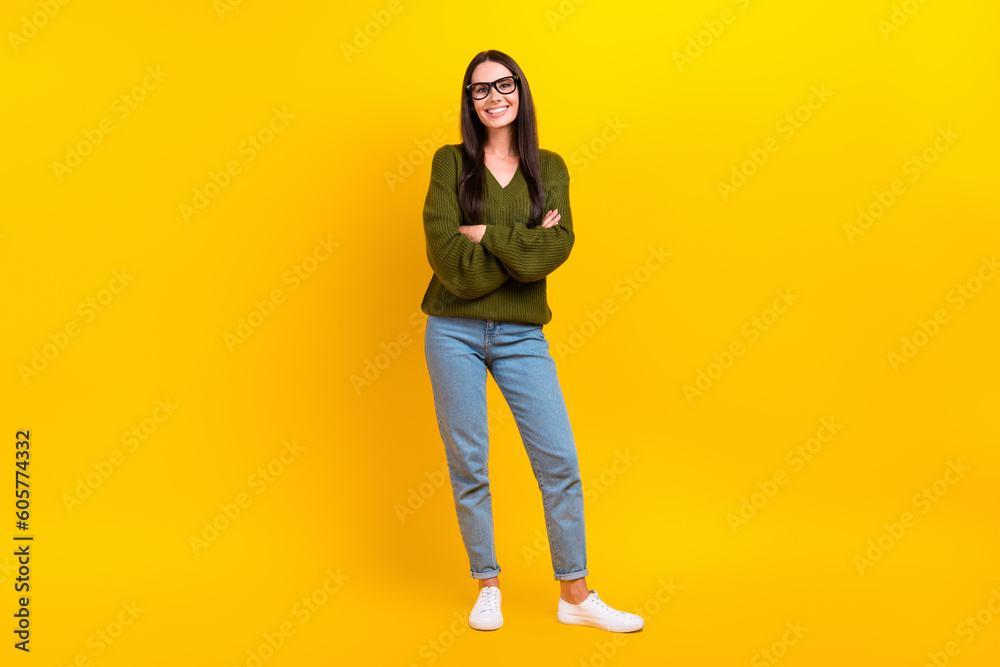 Full length photo of cute confident woman dressed khaki sweater spectacles arms crossed isolated yellow color background Full length photo of cute confident woman dressed khaki sweater spectacles arms crossed isolated yellow color background