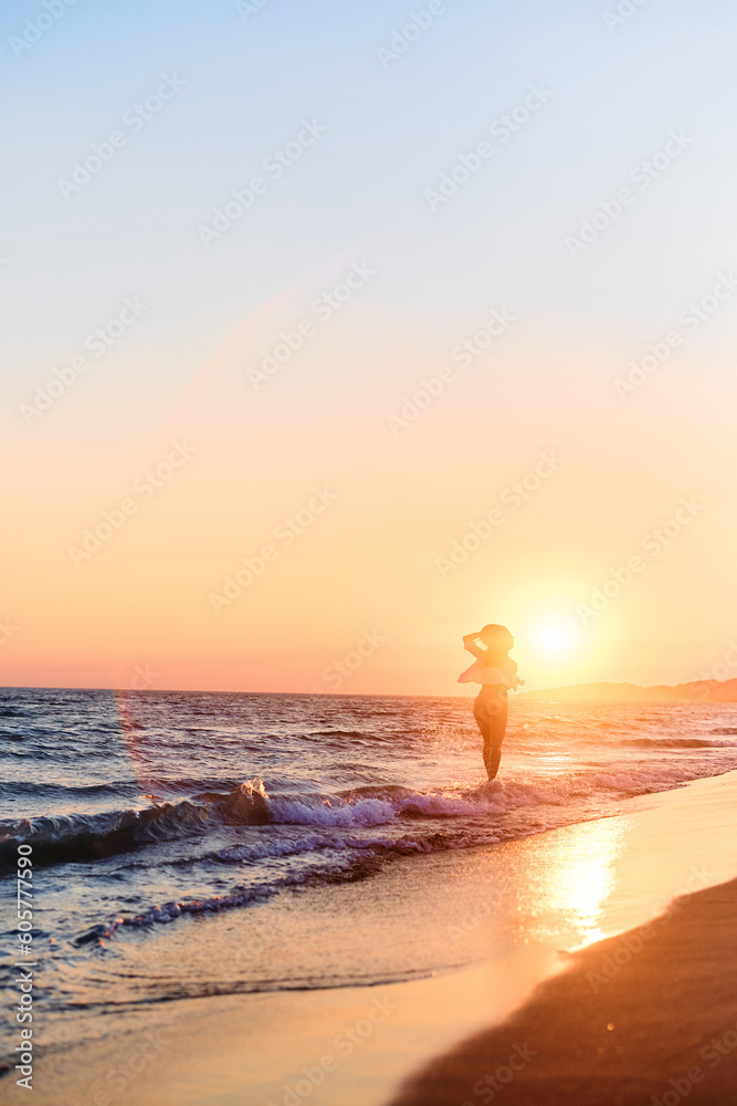 Rear view of woman enjoying in summer sunset at sea.