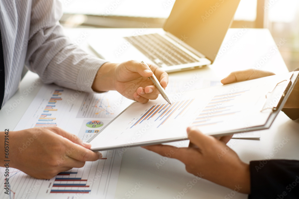 Two business people sitting at workplace and discussing about earnings on a graph to plan investments.