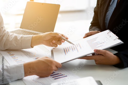 Two business people sitting at workplace and discussing about earnings on a graph to plan investments.