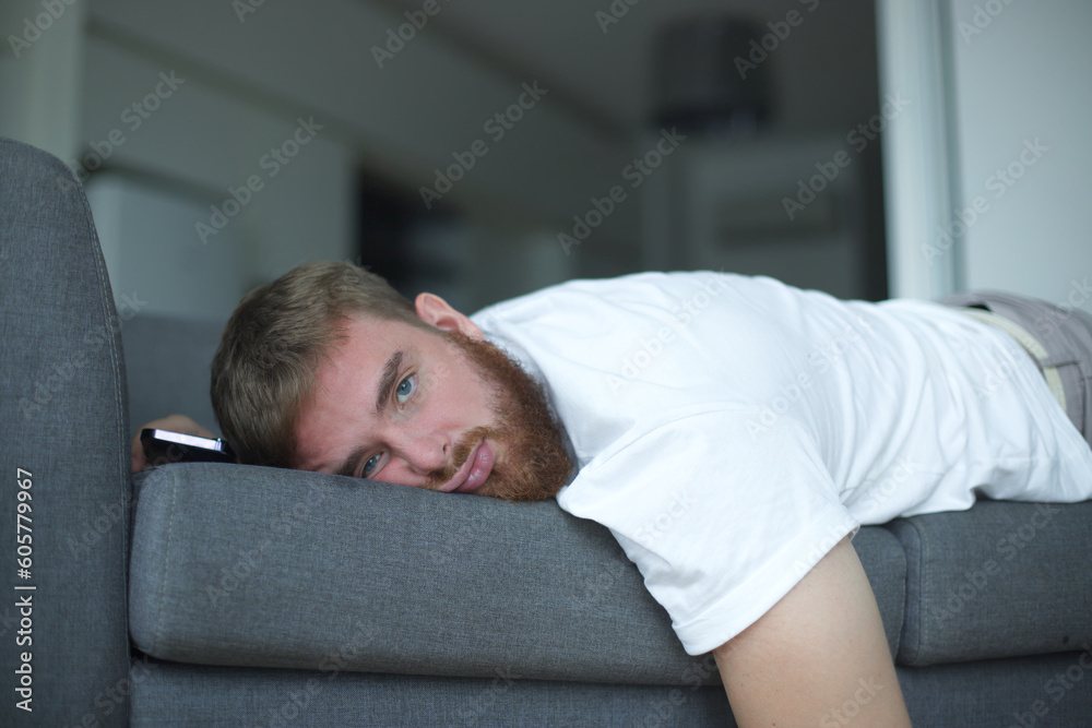 Young bearded man sleep at home on couch with his cell mobile phone in living room. Smartphone addiction concept. Young bearded man sleep at home on couch with his cell mobile phone in living room. Smartphone addiction concept.