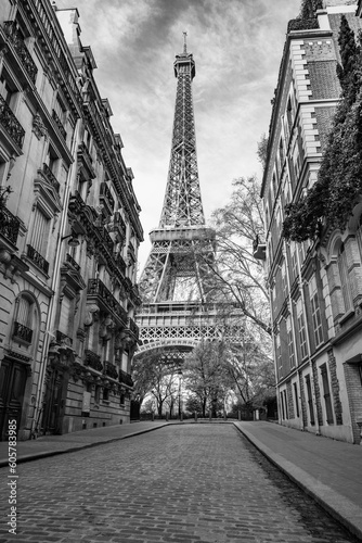 Fototapeta Naklejka Na Ścianę i Meble -  View of the Eiffel Tower from a nearby street full of residential buildings. Paris, France. Black and white photography.