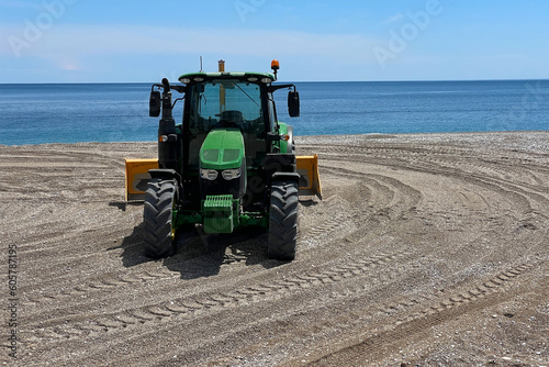 Tractor with a plow for leveling the surface of the sand on a sandy beach before the opening of the tourist season. © aapsky