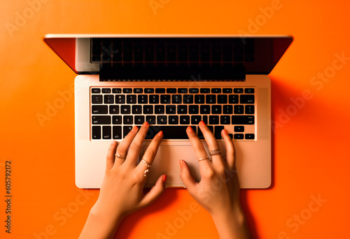people's hands typing on a laptop on an orange background