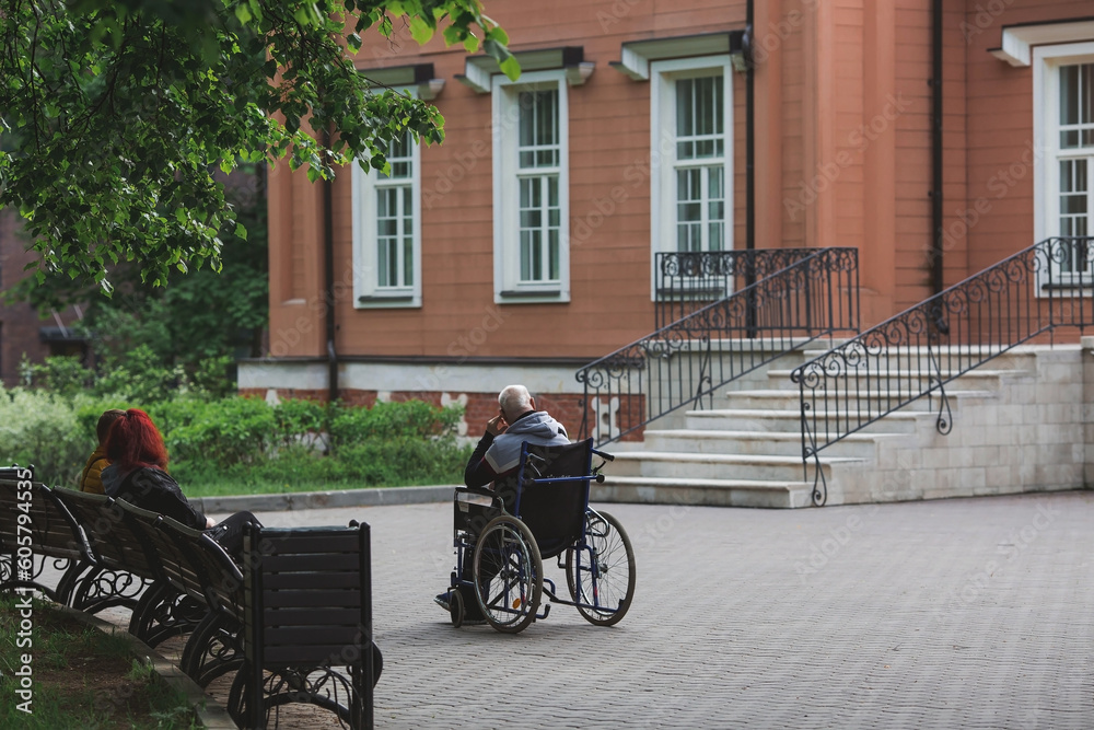 An elderly man in a wheelchair walks in the park outdoors. Disability. Health problems. Medicine, life insurance and healthcare.