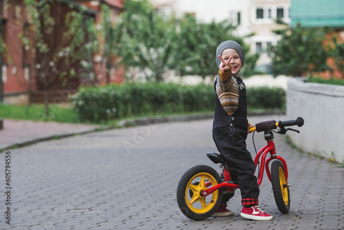 A cheerful little boy rides a bicycle outdoors Fototapet