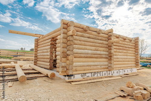 Fototapeta Naklejka Na Ścianę i Meble -  Construction site of wooden mountain house. Traditional log cabin built from wood logs on sunny summer day. Cottage house design
