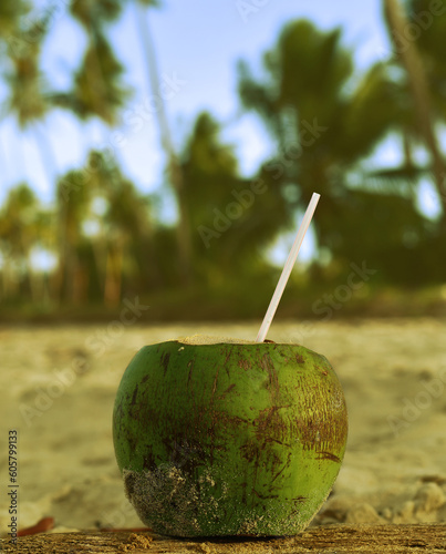 Fresh coconut drink on tropical beach with palm trees in background. Summer concept