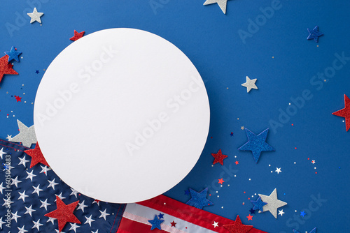 Veterans Day celebration inspiration. Overhead view of iconic party accessories such as sparkling stars, festive confetti and national flags, arranged on blue backdrop with empty circle for text or ad