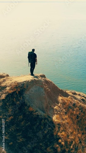 The man standing on the mountain cliff on the seascape background