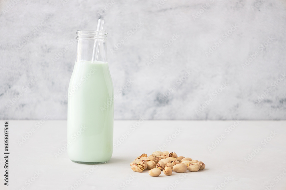 Homemade vegetable milk from pistachio nuts. Pistachio milk in a bottle on a gray concrete table. Ideal for vegans. place for text Homemade vegetable milk from pistachio nuts. Pistachio milk in a bottle on a gray concrete table. Ideal for vegans. place for text