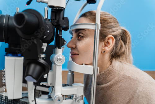 Ophthalmologist illuminates eye of child with light from slit lamp to diagnose the eyes and cornea. Pediatric ophthalmologist with slit lamp examines eyes and cornea of child.