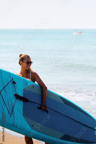 Happy woman with surfboard during summer day on beach.