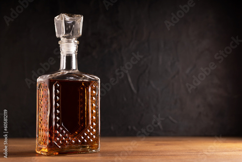 Whiskey or rum with an ice cube on a wooden table with a black background