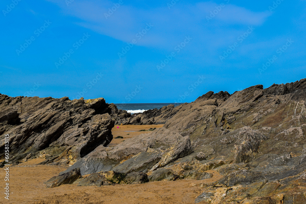rocks and rockpools golden sand at the beach in spring summer with blue skies