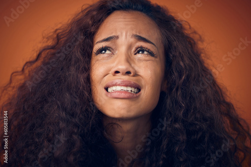 Woman, crying and sad face in studio with anxiety, mental health problem and depression. Headshot of african female person on a brown background for cry emoji, psychology and broken heart with tears
