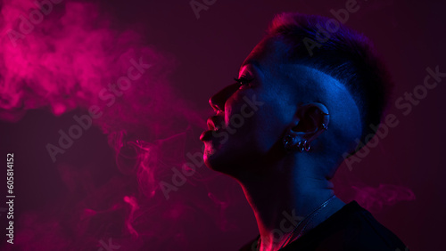 Profile Asian woman with short haircut smoking in neon light.