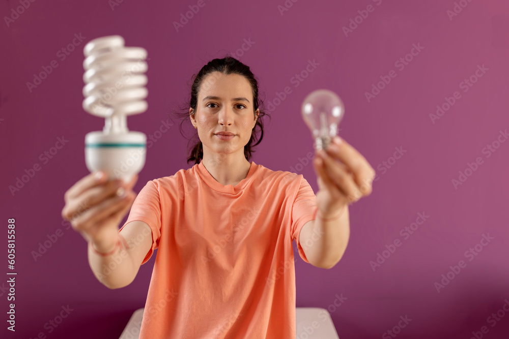 Comparison economic and normal light bulb..Eco living and sustainability concept - smiling woman comparing energy saving light bulb with incandescent lamp Comparison economic and normal light bulb..Eco living and sustainability concept - smiling woman comparing energy saving light bulb with incandescent lamp