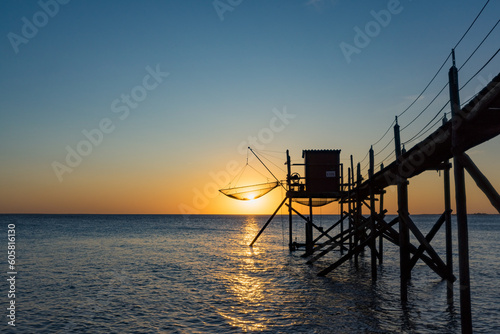 A fishing hut called carrelet with craft lifting net at sunset. Esnandes, charente maritime, France. The sun is caught in the net.