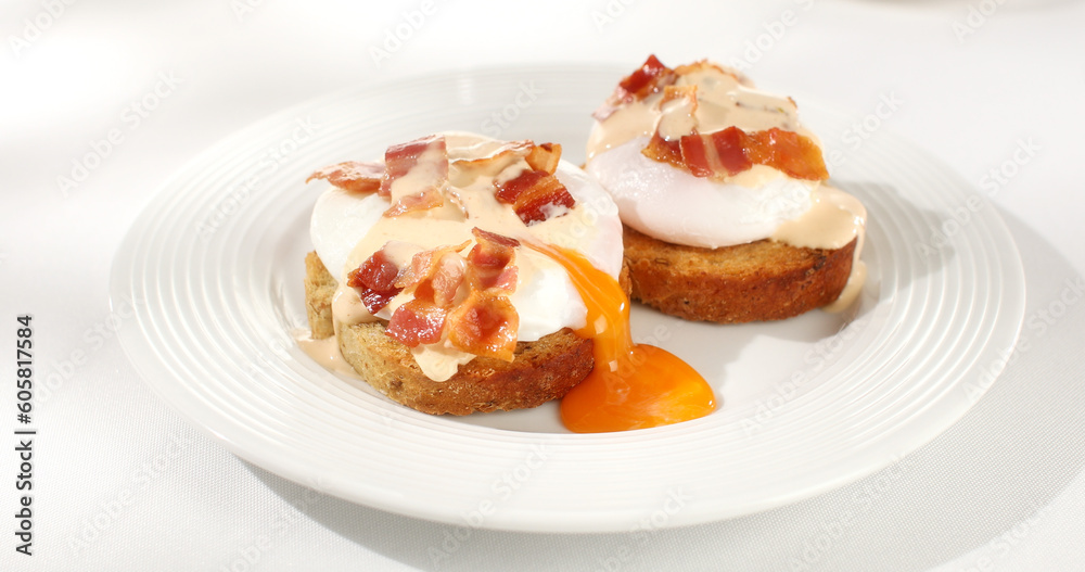 toast with poached egg and bacon on a plate. serving breakfast on a white background. sunny day. angle view. toast with poached egg and bacon on a plate. serving breakfast on a white background. sunny day. angle view.
