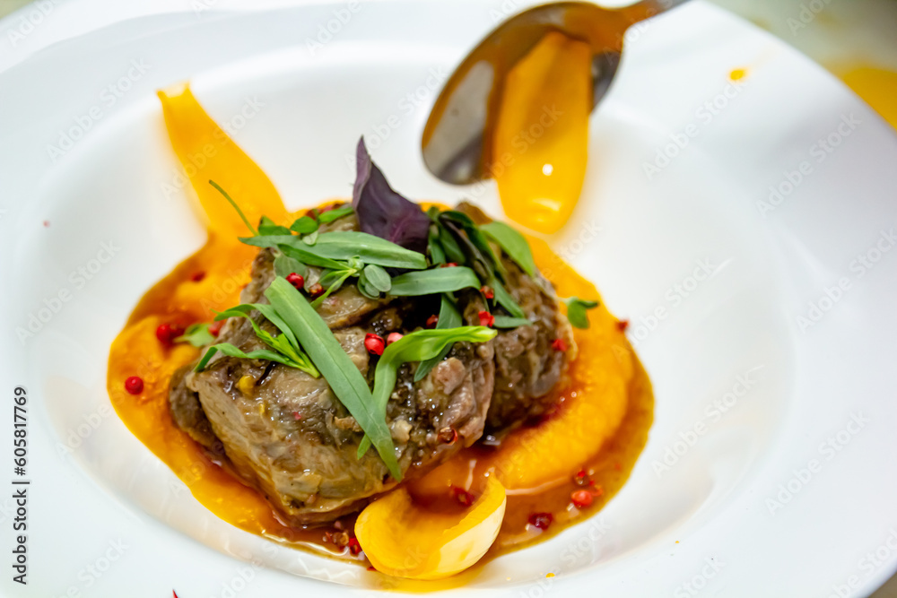 A deliciously appetizing pumpkin puree with chunks of beef meat with spices and herbs in a green plate on a dark stone table. A hearty lunch in a restaurant. Meat with vegetables in the oven