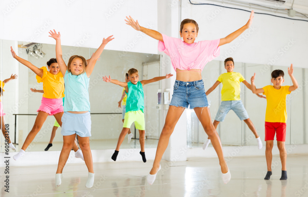 Group of cheerful tweens having fun and jumping during modern dances class.