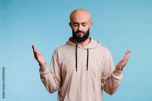 Fotografie Arab man praying to god with open hands and closed eyes, pleading for blessing and forgiveness