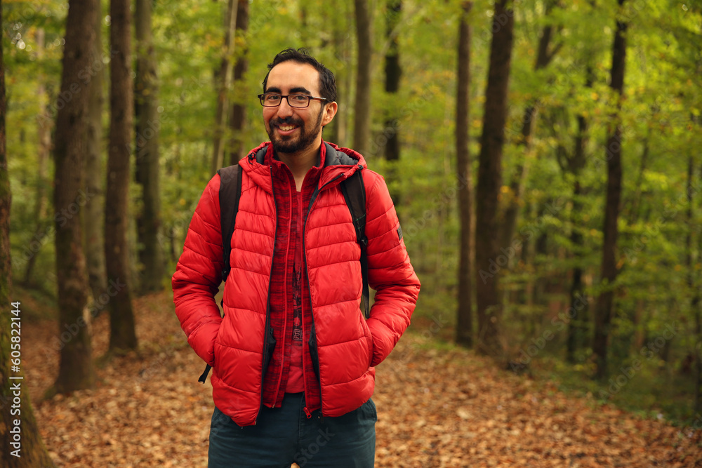 Trekking lover, adventurer bearded Caucasian man posing in front of a green blurry background in the forest. Copy space for text, advertising, message, logo