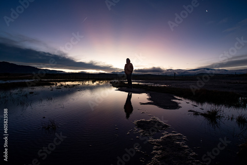 Sunset on the mountain with full human figure in backlight, reflection in the water