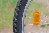 Orange reflector on the bicycle wheel. Safety device. Bike wheel reflector.