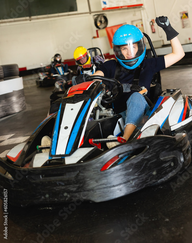 Portrait of female racer in helmet driving kart at the track