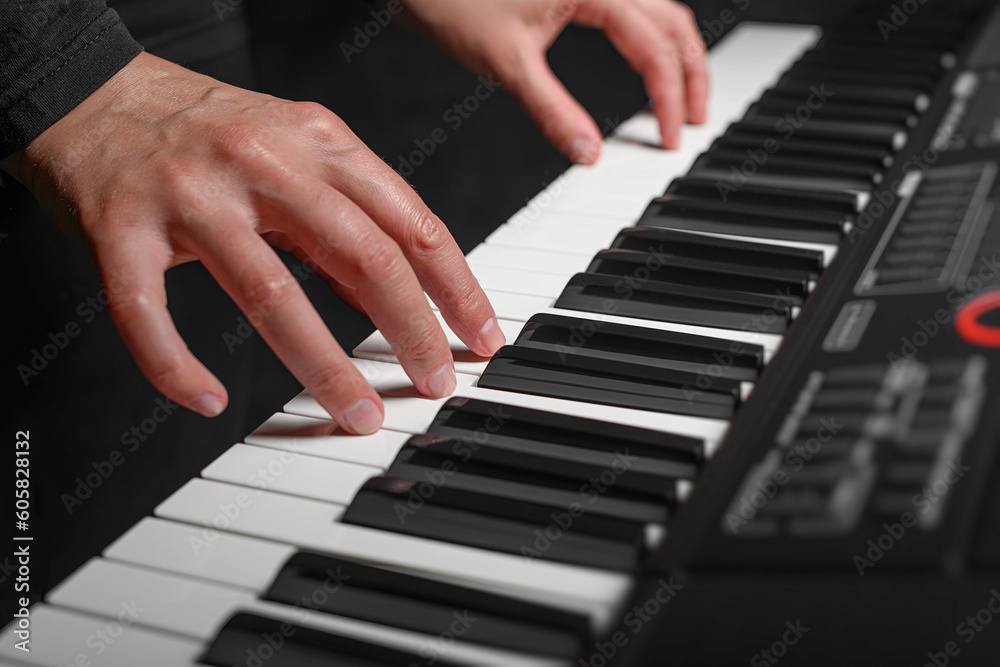 Fototapeta premium Playing a synthesizer on a dark background. The musician plays the synthesizer.