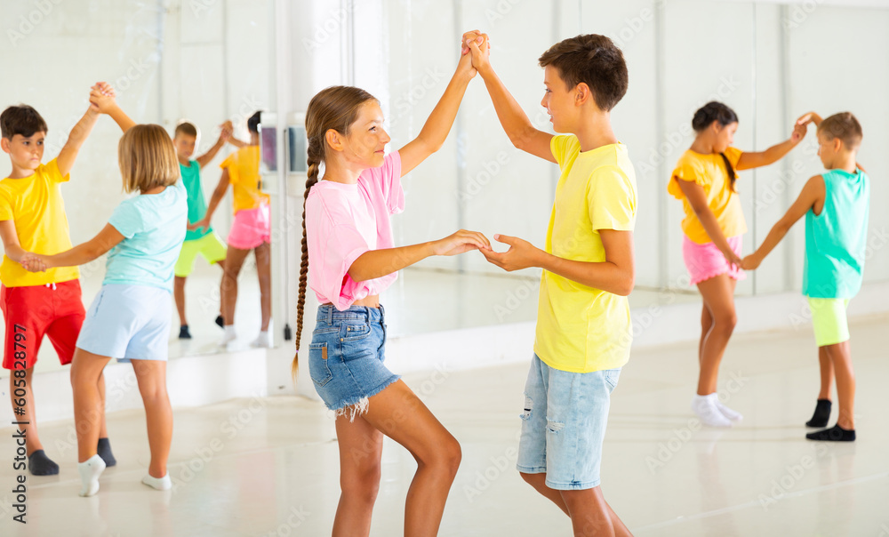 Young boys and girls dancing salsa in studio during group training.