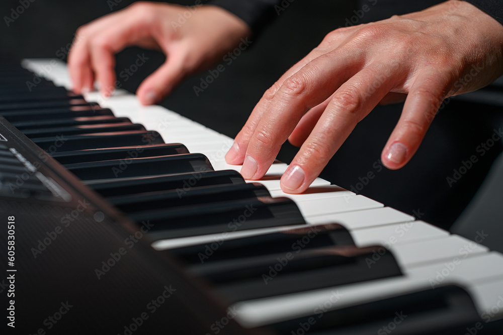 Playing a synthesizer on a dark background. The musician plays the synthesizer.