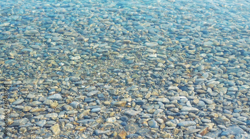 Photo of a calm transporent water surface with pebbles stone under water surface